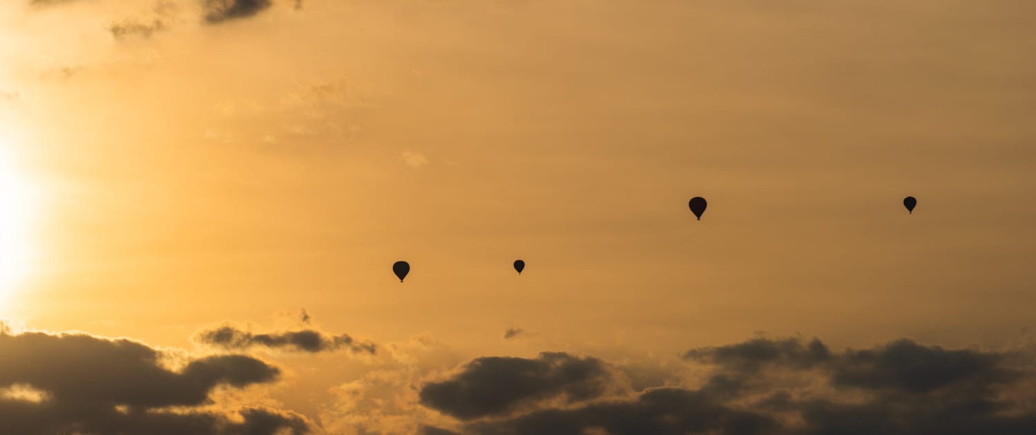 Vier luchtballonnen bij ondergaande zon in Turquant