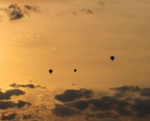 Vier luchtballonnen bij ondergaande zon in Turquant