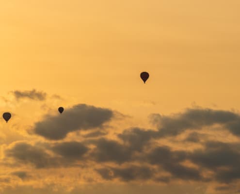 Vier luchtballonnen bij ondergaande zon in Turquant